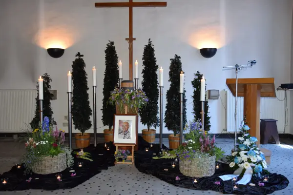 Trauerhalle mit Gedenkbild, Kerzen und Blumenarrangements