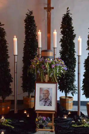 Gedenkbild mit Blumenschmuck unter dem Kreuz